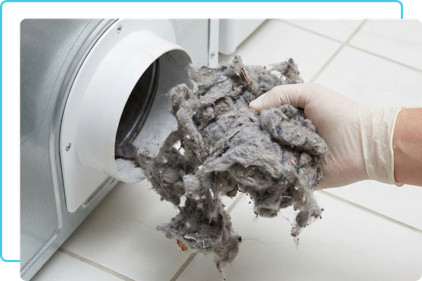 A gloved hand removing a large blockage of lint and debris from a dryer vent connection.
