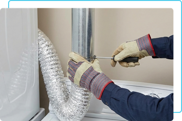 A technician repairing a dryer vent system by installing a rigid metal transition hose behind a dryer.